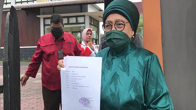 TOKOH masyarakat Riau, Hj Azlaini Agus, memperlihatkan tanda terima laporan yang dibuatnya terhadap dugaan penistaan agama terhadap pernyataan Menteri Agama, Yaqut Cholil Qoumas tentang suara azan, Sabtu (26/2/2022), di halaman Mapolda Riau. 