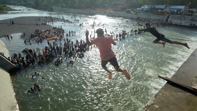 Dua remaja melompat di kawasan Cek Dam Koto Tuo, Padang, Sumatera Barat, Senin (12/4/2021). Warga menjalankan tradisi "Balimau" atau mensucikan diri menjelang memasuki satu Ramadhan dengan mandi bersama keluarga dan kerabat di sungai. ANTARA FOTO/Iggoy el Fitra