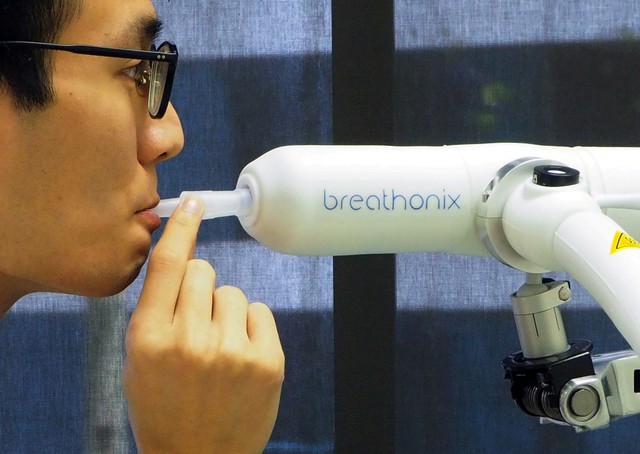 Seorang anggota staf mendemonstrasikan penggunaan alat tes breathalyzer Breathonix yang dikembangkan oleh Singapura.  Foto: REUTERS/Chen Lin