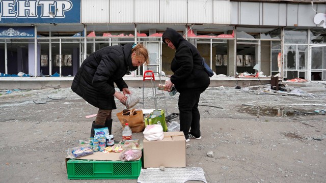 Wanita mengatur barang untuk dijual di pasar lokal selama konflik Ukraina-Rusia di kota pelabuhan selatan Mariupol, Ukraina, Selasa (19/4/2022). Foto: Alexander Ermochenko/Reuters