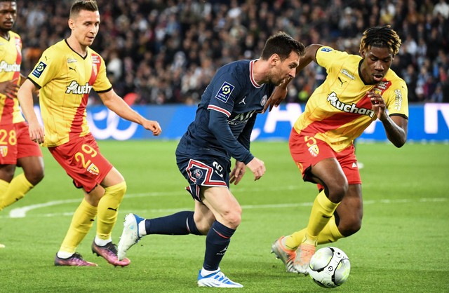 Penyerang Paris Saint-Germain Lionel Messi (tengah) berebut bola dengan bek Lens asal Prancis Christopher Wooh (kanan) pada pertandingan sepak bola L1 Prancis antara Paris-Saint Germain (PSG) dan RC Lens di Stadion The Parc des Princes (23/4/2022). Foto: BERTRAND GUAY / AFP