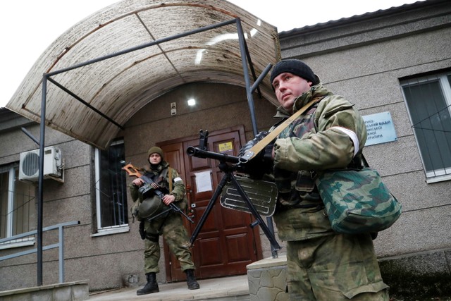 Prajurit milisi pro-Rusia berjaga di luar kantor kejaksaan di Stanytsia Luhanska, Luhansk, Ukraina.  Foto: Alexander Ermochenko/REUTERS