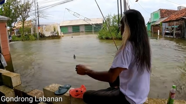 YouTuber Gondrong Labanan memancing di jalan raya yang terendam banjir. Foto: Tangkapan Layar YouTube Gondrong Labanan