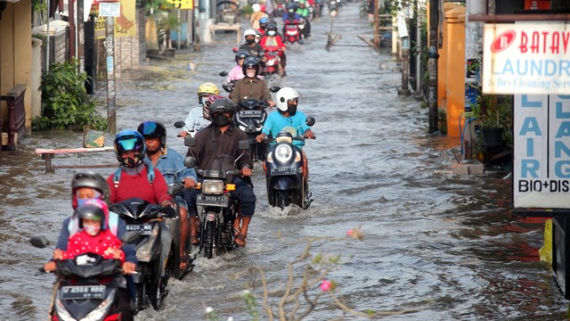 Pengendara motor melintas di jalan yang tergenang banjir di Desa Kureksari, Waru, Sidoarjo, Jawa Timur, Jumat (11/3/2022). Foto: Umarul Faruq/ANTARA FOTO
