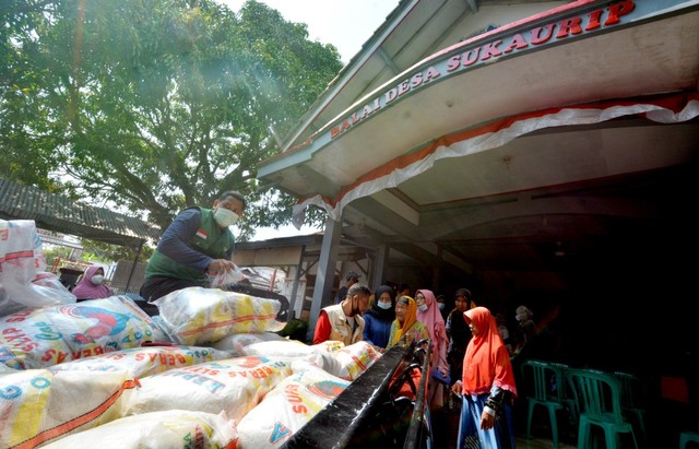 Pengurus Bazma RU VI Balongan menyalurkan bantuan beras kepada warga penerima manfaat. 
