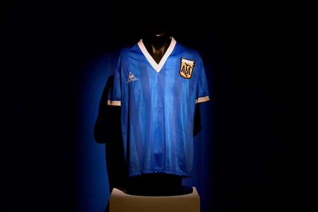 Petugas menunjukkan kaus yang dikenakan oleh pemain sepak bola Argentina Diego Maradona di Piala Dunia 1986, sebelum dilelang oleh Sotheby's, di London, Inggris. Foto: Toby Melville/REUTERS
