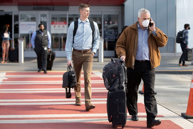 Beberapa orang terlihat menggunakan masker dan tanpa masker meninggalkan terminal domestik Bandara Internasional Hartsfield-Jackson Atlanta di Atlanta, Georgia, Amerika Serikat, Selasa (19/4/2022). Foto: Alyssa Pointer/Reuters