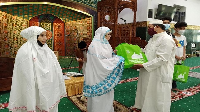 DUA orang perempuan memakai mukena menerima buah tangan dari Mualaf Center usai menyatakan diri memeluk agama Islam di Masjid Agung An-Nur, Pekanbaru, belum lama ini. 