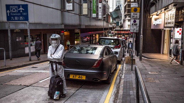 Seorang pria yang mengenakan alat pelindung diri (APD) berdiri di sebuah jalan di Hong Kong (8/3). Foto: PETER PARKS / AFP