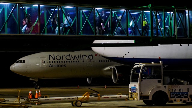 Turis Rusia berjalan menuju pesawat penerbangan charter ke Rusia di bandara Juan Gualberto Gomez di Varadero, Kuba pada (6/3). Foto: YAMIL LAGE/AFP