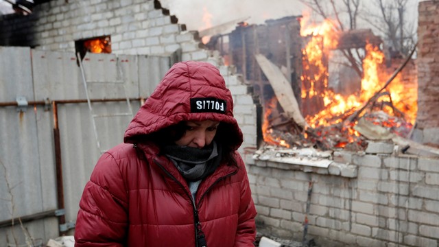 Seorang penduduk setempat berdiri di samping rumahnya yang terbakar akibat serangan, di kota Donetsk yang dikuasai separatis, Ukraina, Senin (28/2/2022). Foto: Alexander Ermochenko/REUTERS