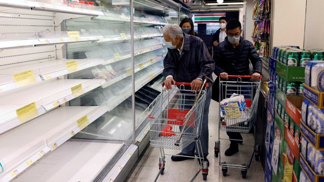 Pelanggan yang mengenakan masker berbelanja di depan rak yang sebagian kosong di supermarket selama wabah penyakit coronavirus (COVID-19) di Hong Kong. Foto: REUTERS/Tyrone Siu