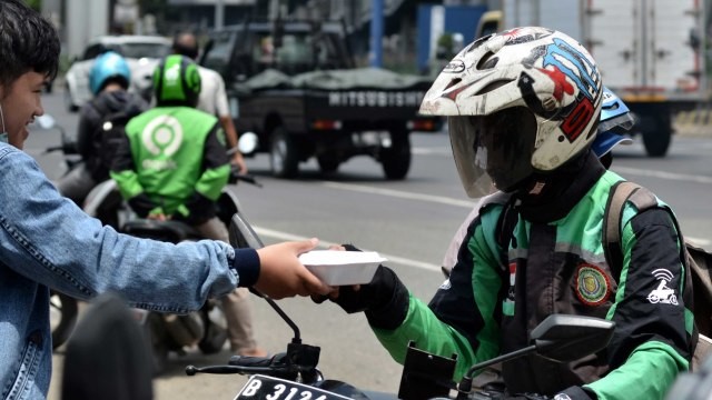 Warga membagi-bagikan makan siang gratis kepada pengemudi ojek online (ojol) di Bekasi, Jawa Barat, Kamis (2/4/2020) Foto: ANTARAFOTO/Suwandy
