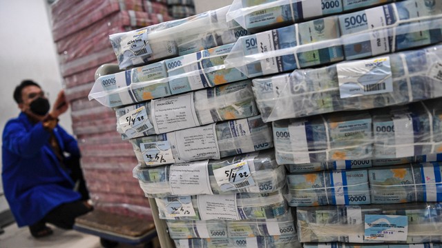 Pegawai menghitung uang tunai pecahan Rp100 ribu dan Rp50 ribu yang akan dikirimkan ke kantor cabang di Sentra Kas Bank Mandiri, Jakarta, Rabu (6/4/2022). Foto: M Risyal Hidayat/ANTARA FOTO