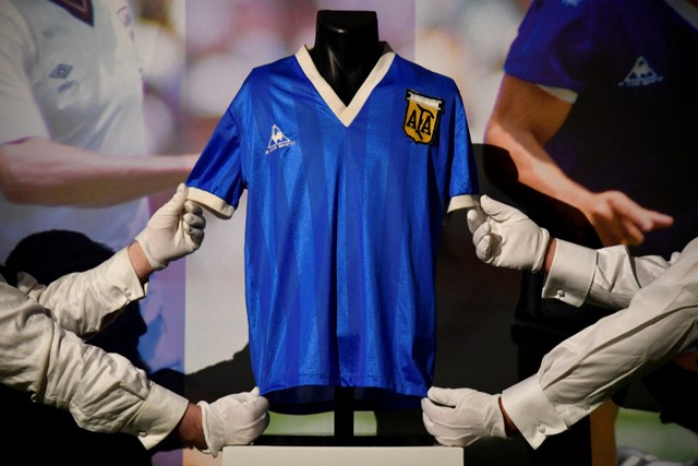 Petugas menunjukkan kaus yang dikenakan oleh pemain sepak bola Argentina Diego Maradona di Piala Dunia 1986, sebelum dilelang oleh Sotheby's, di London, Inggris. Foto: Toby Melville/REUTERS