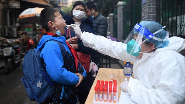 Seorang anak mengikuti tes swab massal untuk mencegah penyebaran COVID-19 di Wuhan di Hubei Tengah, China, Jumat (4/3/2022). Foto: STR/AFP
