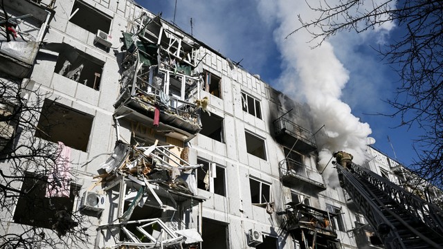 Petugas pemadam kebakaran bekerja pada kebakaran di sebuah gedung setelah pemboman di kota Chuhuiv, Ukraina timur, Ukraina, Kamis (24/2/2022). Foto: Aris Messinis/AFP