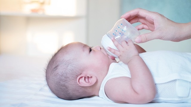 Ilustrasi bayi pegang botol susu sendiri. Foto: Thannaree Deepul/Shutterstock