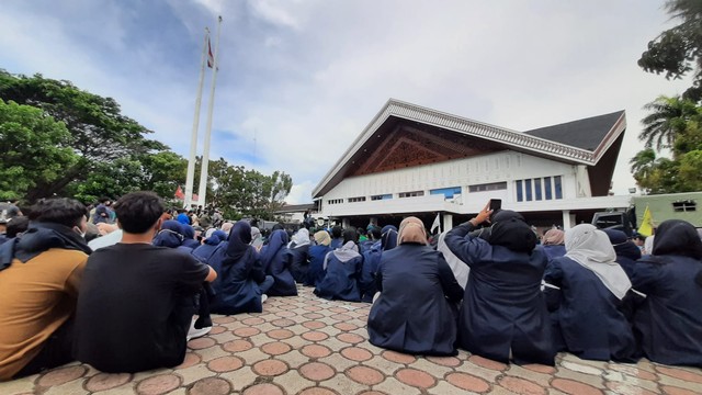 Dalam aksi demo 11 April 2022 di Banda Aceh, massa ratusan mahasiswa, anggota DPRA, hingga polisi yang mengawal bersila di tanah. Foto: Habil Razali/acehkini