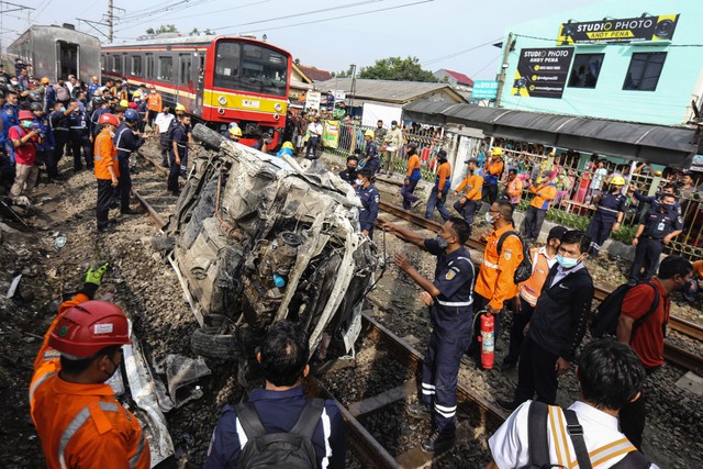 Sejumlah petugas melakukan evakuasi mobil yang tertabrak KRL di kawasan Rawageni, Cipayung, Depok, Jawa Barat, Rabu (20/4/2022). Foto: Asprilla Dwi Adha/ANTARA FOTO