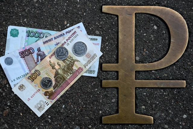 Koin dan uang kertas rubel Rusia di sebelah tanda rubel Rusia. Foto: Kirill K / AFP