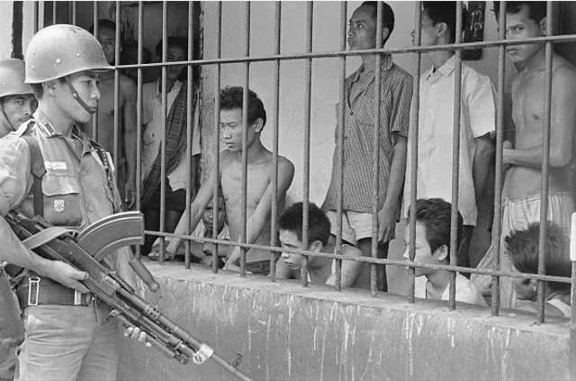 Seorang tentara mengawasi para tahanan politik komunis di Tangerang, Oktober 1965. Foto: Getty Images.