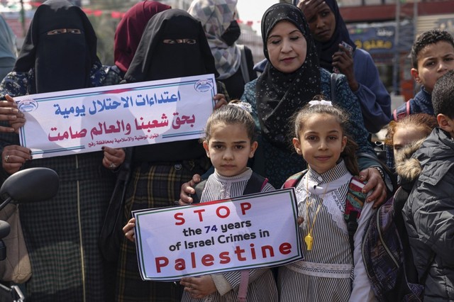 Warga Palestina mengangkat plakat menuntut dukungan internasional serupa untuk Palestina melawan Israel seperti dukungan terhadap Ukraina melawan Rusia di kamp pengungsi Rafah di Jalur Gaza selatan pada Senin (7/3/2022)
 Foto: Said Khatib/AFP