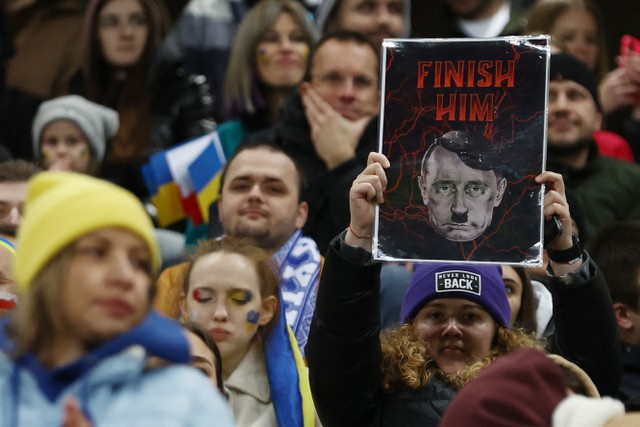 Seorang suporter wanita membawa poster bergambar Presiden Rusia Vladmir Putin di Stadion Legii, Warsawa, Polandia, Selasa (12/4/2022). Foto: Kacper Pempel/Reuters