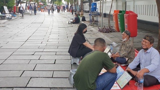 Abah Yadi (baju biru) dan rekannya sedang melayani klien di Kota Tua Jakarta. Foto: Hanny Nurulhade P