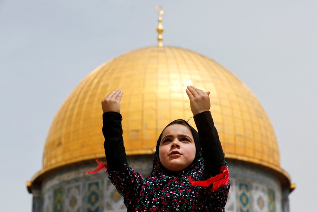 Seorang gadis muslim berdiri saat warga Palestina melaksanakan salat Jumat pertama di bulan ramadhan di kompleks Masjid Al-Aqsa.  Foto: Ammar Awad/REUTERS
