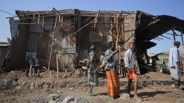 Warga berdiri di samping rumah yang hancur akibat serangan udara selama pertempuran antara Pasukan Pertahanan Nasional Ethiopia (ENDF) dan pasukan Front Pembebasan Rakyat Tigray (TPLF) di kota Kasagita, Afar, Ethiopia, Jumat (25/2/2022). Foto: Tiksa Negeri/REUTERS