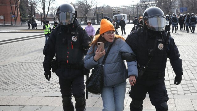 Polisi Rusia menahan seorang wanita selama demonstrasi tanpa sanksi di Lapangan Manezhnaya di depan Kremlin, 13 Maret 2022, di Moskow.