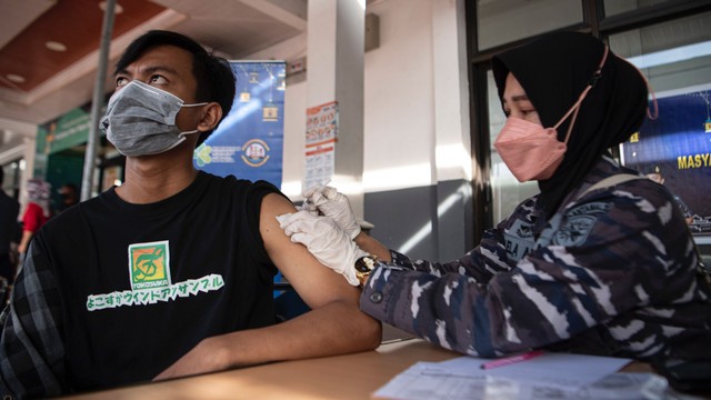 Prajurit Pangkalan TNI Angkatan Laut (Lanal) Palembang menyuntikkan vaksin COVID-19 dosis ketiga atau booster kepada pemudik di Stasiun Kertapati Palembang Sumatera Selatan, Sabtu (23/4/2022). Foto: Nova Wahyudi/ANTARA FOTO