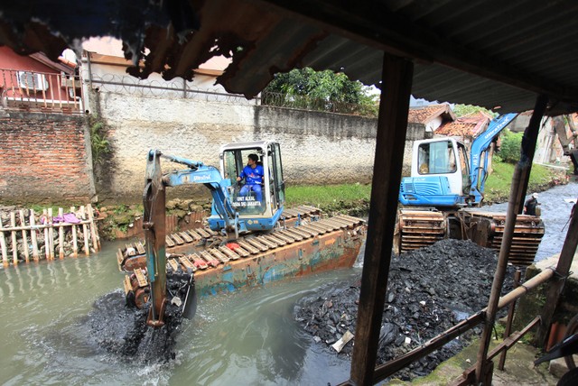 Petugas menggunakan alat berat saat mengeruk endapan tanah dan lumpur di Kali Mampang, Jakarta, Senin (21/2/2022). Foto: Reno Esnir/ANTARA FOTO