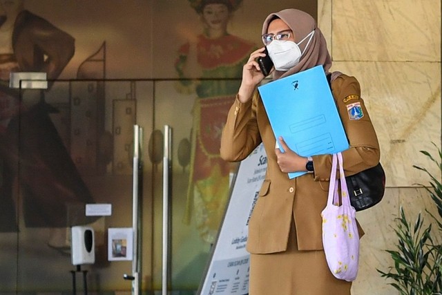 Seorang pegawai Aparatur Sipil Negara (ASN) bersiap meninggalkan ruangan sembari menggunakan telefon genggam pada hari pertama saat bulan Ramadhan 1443 Hijriah di Gedung Balai Kota DKI Jakarta, Senin (4/4/2022).  Foto: M Risyal Hidayat/ANTARA FOTO