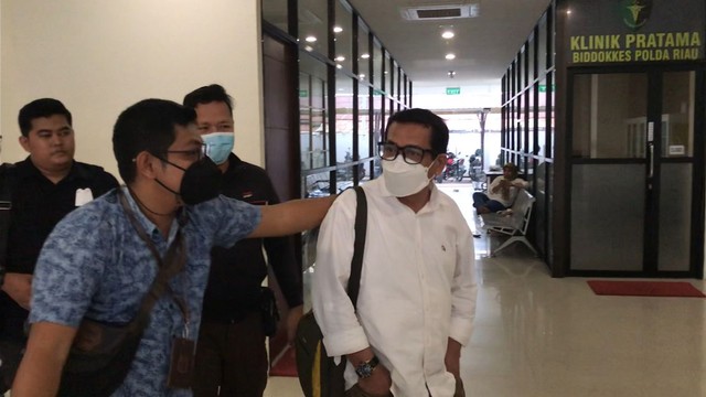 DEKAN FISIP Universitas Riau, Syafri Harto (baju putih), keluar dari ruangan Tahanan Polda Riau usai divonis bebas oleh Majelis Hakim Pengadilan Negeri (PN) Pekanbaru, Rabu (30/3/2022). Ia dibawa ke Rutan Sialang Bungkuk untuk menjalani proses administrasi pembebasan.  (FOTO: SELASAR RIAU/RAMADHI DWI PUTRA) 