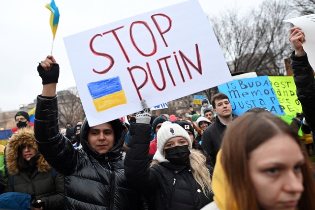 Warga membentangkan bendera Ukraina dan papan penolakan atas aksi Vladimir Putin melakukan invasi Rusia ke Ukraina di Lafayette Square, Washington, DC (24/02/2022). Foto: Mandel Ngan/AFP