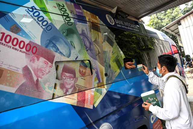 Warga menerima uang baru yang ditukarkan pada mobil kas keliling Bank Indonesia (BI) di Pasar Koja Baru, Jakarta Utara, Rabu (13/4/2022). Foto: M Risyal Hidayat/ANTARA FOTO