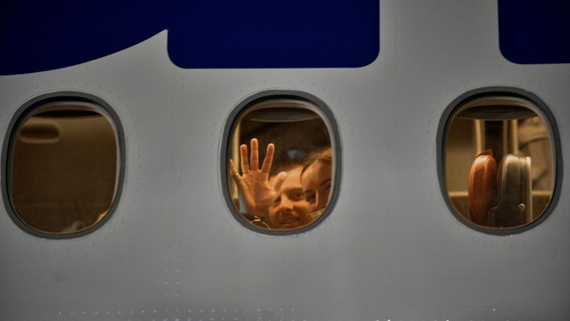 Turis Rusia melambai dari penerbangan charter ke Rusia di bandara Juan Gualberto Gomez di Varadero, Kuba pada (6/3). Foto: YAMIL LAGE/AFP