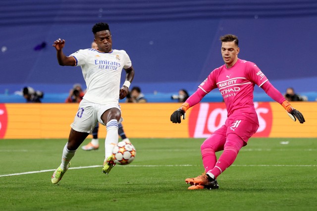 Pemain Real Madrid Vinicius Junior berusaha melewati penjaga gawang Manchester City Ederson pada pertandingan leg kedua semifinal Liga Champions di Santiago Bernabeu, Madrid, Spanyol. Foto: Carl Recine/REUTERS