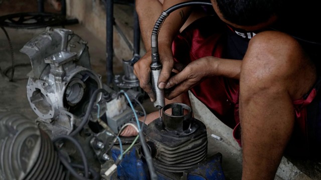 Seorang montir salah satu bengkel balap mempersiapkan pengaturan mesin motor. Foto: Iqbal Firdaus/kumparan