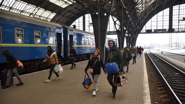 Penumpang, termasuk pengungsi dari kota Sumy dan Kyiv, berjalan di sepanjang peron stasiun kereta api setibanya mereka di Lviv, Ukraina, Jumat (25/2/2022). Foto: Pavlo Pamararchuk/REUTERS