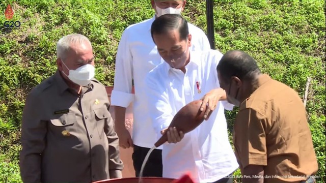 Presiden Jokowi menuangkan air yang diisi pada Jiwaq, sejenis kendi dari Papua yang terbuat dari labu botol. (Foto: Biro Pers)