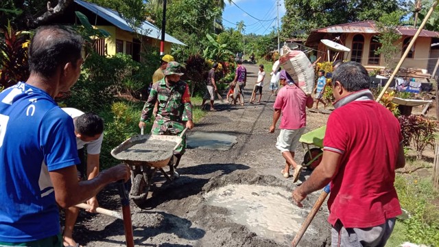 Personil Bintara Pembina Desa (Babinsa) Koramil 1301-08/Tabteng, Sertu Rigman Antore, gotong royong bersama warga untuk memperbaiki jalan rusak di desa tersebut. 