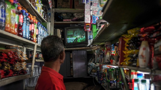 Seorang pedagang menonton siaran TV analog di Antapani, Bandung, Jawa Barat, Kamis (17/2/2022). Foto: Raisan Al Farisi/ANTARA FOTO