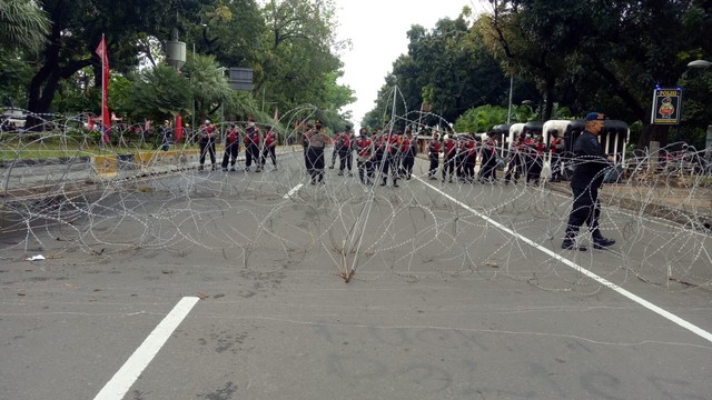 Aparat kepolisian menutup ruas jalan dengan kawat berduri di jalan Medan Merdeka Barat pada Kamis (21/4/2022). Foto: Aprilandika Pratama/kumparan
