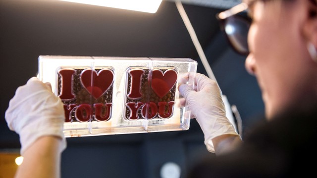 Salah satu pekerja menunjukkan cokelat yang baru dibuat di pabrik cokelat rumahan "Amel" di Pristina, Kosova, Sabtu (12/2). Foto: Armend Nimani/AFP