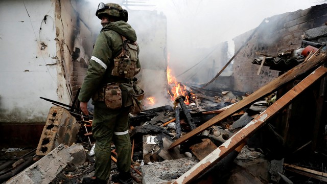 Seorang prajurit milisi pro-Rusia berjalan di dalam sebuah rumah yang rusak, di kota Donetsk yang dikuasai separatis, Ukraina, Senin (28/2/2022). Foto: Alexander Ermochenko/REUTERS