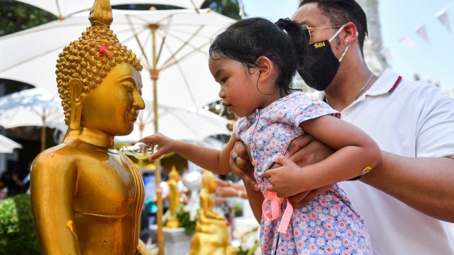 Beberapa orang menyemprotkan air wangi tradisional pada patung Buddha. Foto: Chalinee Thirasupa/REUTERS/Kumparan