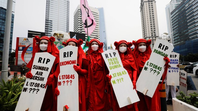 Orang-orang menggunakan kostum dan membawa papan nisan dalam aksi protes perubahan iklim di Jakarta, Jumat (25/3/2022). Foto: Willy Kurniawan/REUTERS